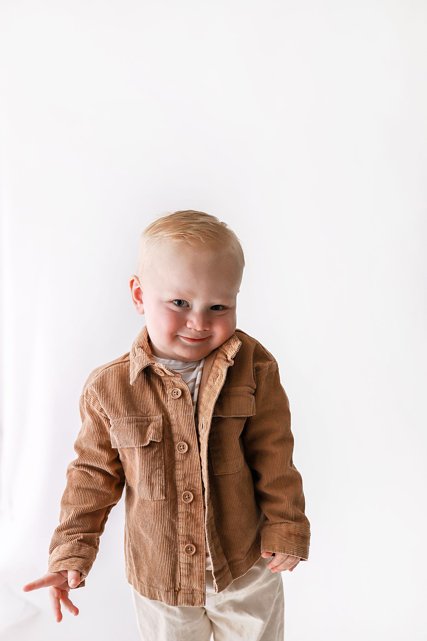 Smiling toddler with blond hair against a bright white background. Utah baby photographer