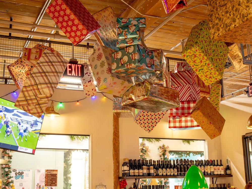 Colorful fabric gift wrap pieces hanging as ceiling decorations inside a festive holiday market shop.