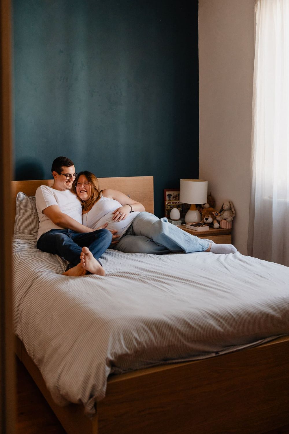 Couple attendant un enfant assis sur le lit, un moment tendre et complice capture par une photographe de grossesse a domicile a Armentieres