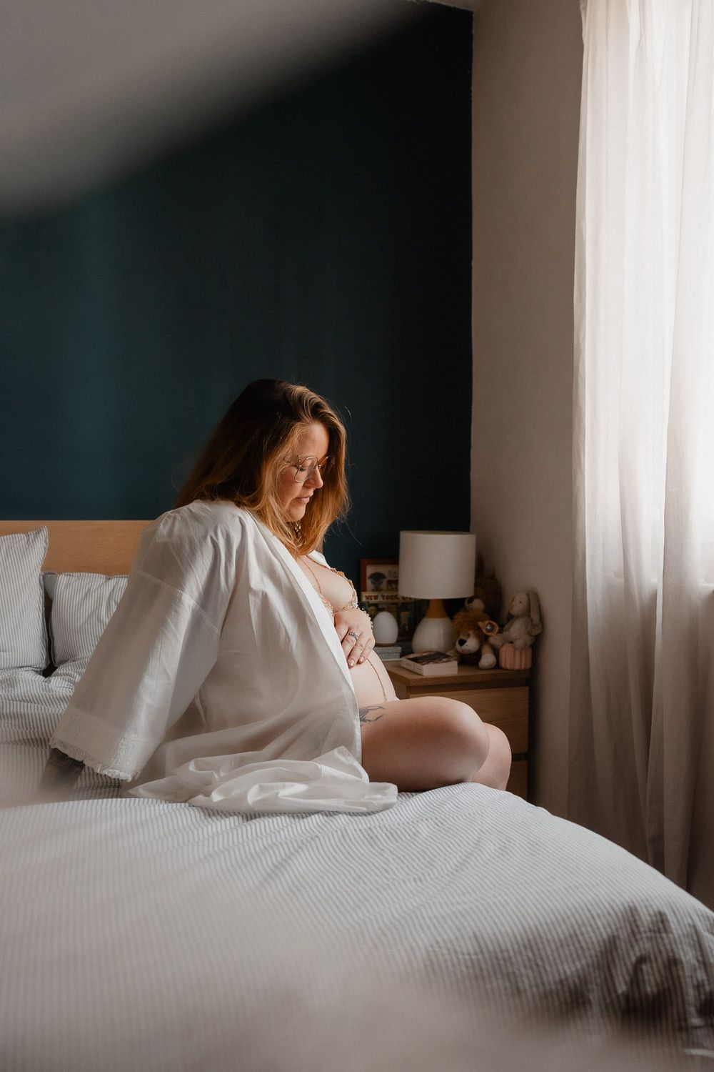 Future maman dans sa chambre baignee de lumiere naturelle, un portrait cree par une photographe de grossesse a Lille