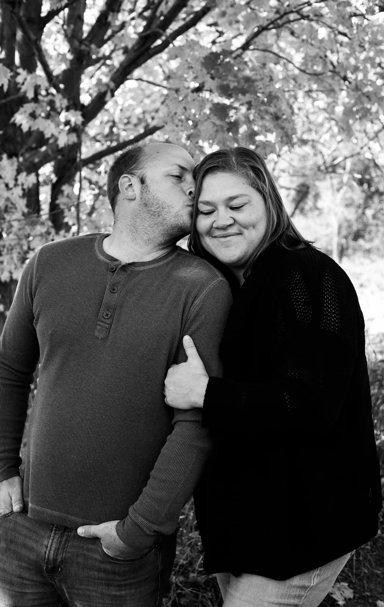 Intimate black and white portrait of couple sharing tender moment outdoors.