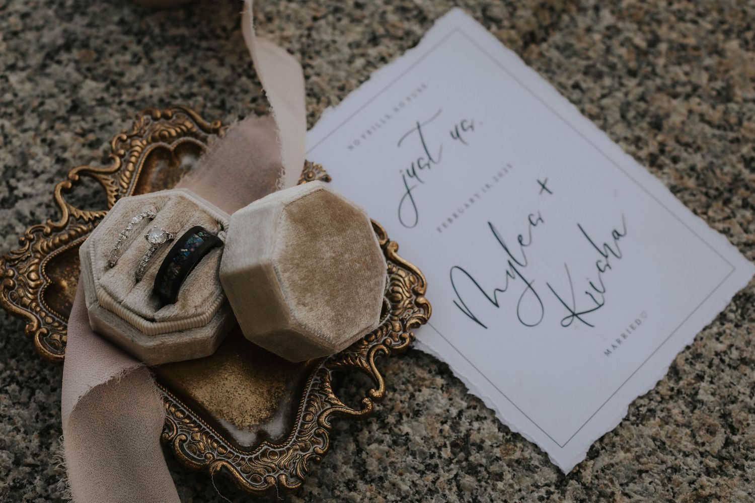 Elegant wedding details including handwritten notes and delicate ribbons arranged on a textured stone surface.