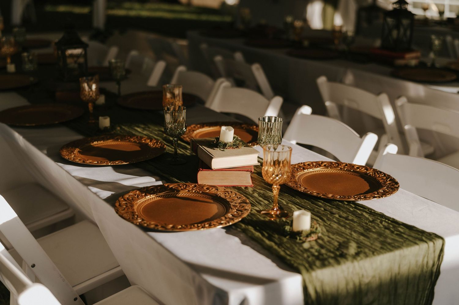 Elegant wedding reception table setting with gold chargers and green table runners.