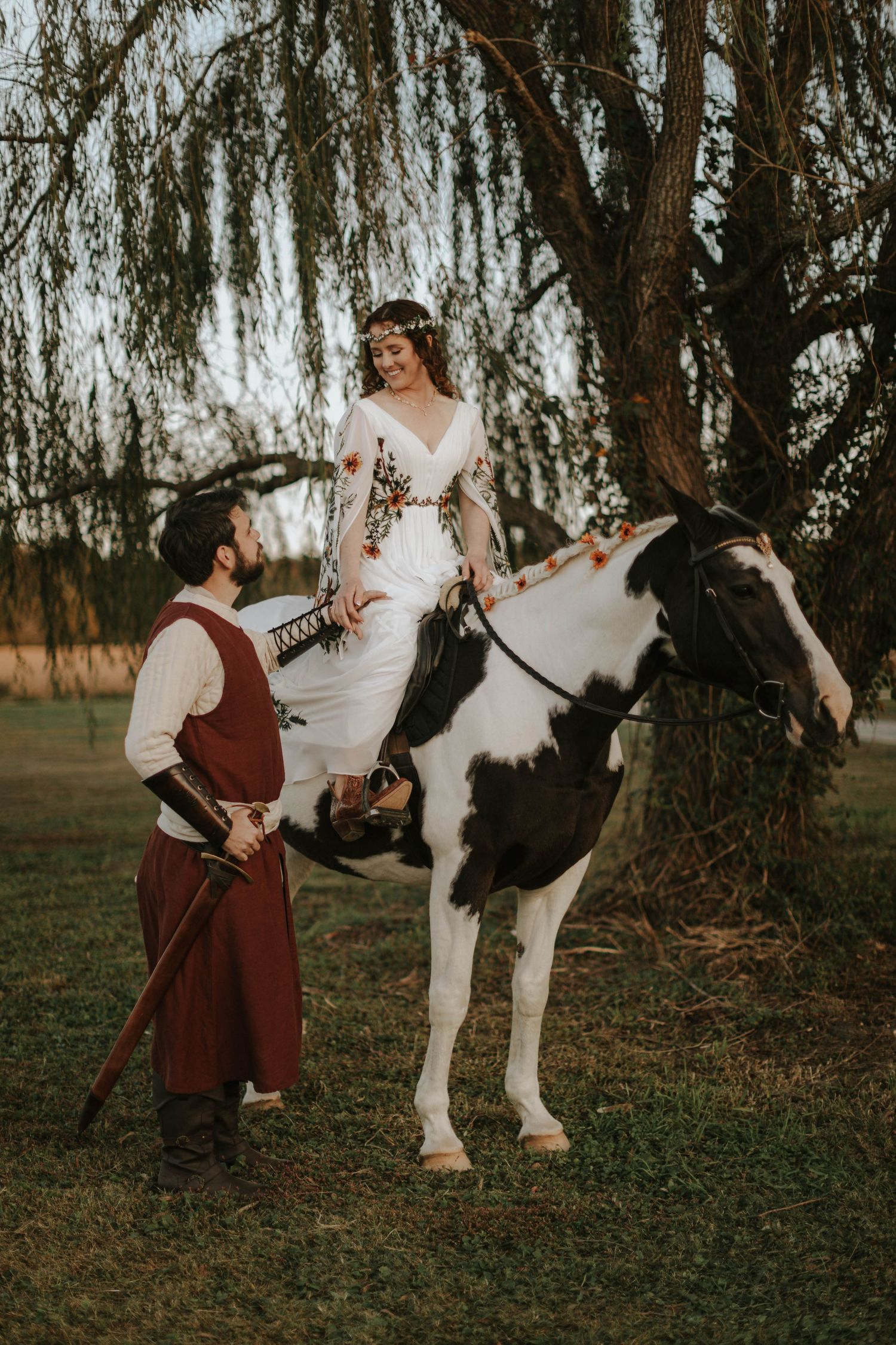 A whimsical wedding photoshoot with a decorative white horse in a pastoral setting.