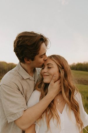 Romantic sunset portrait of a couple sharing an intimate moment in a field.