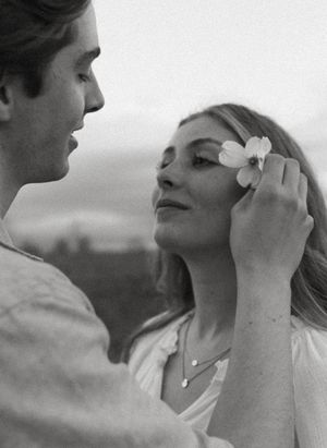 A gentle moment between two people as a flower is placed in her hair.