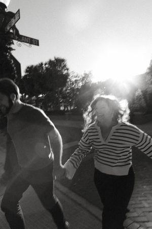 A couple dances together on a street at dusk in black and white.