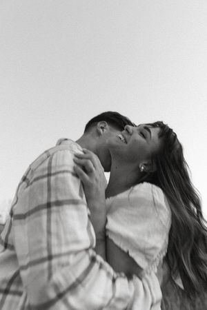 Intimate black and white portrait of a couple embracing in a candid moment.