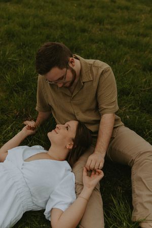 A romantic couple shares an intimate moment while laying in the grass.