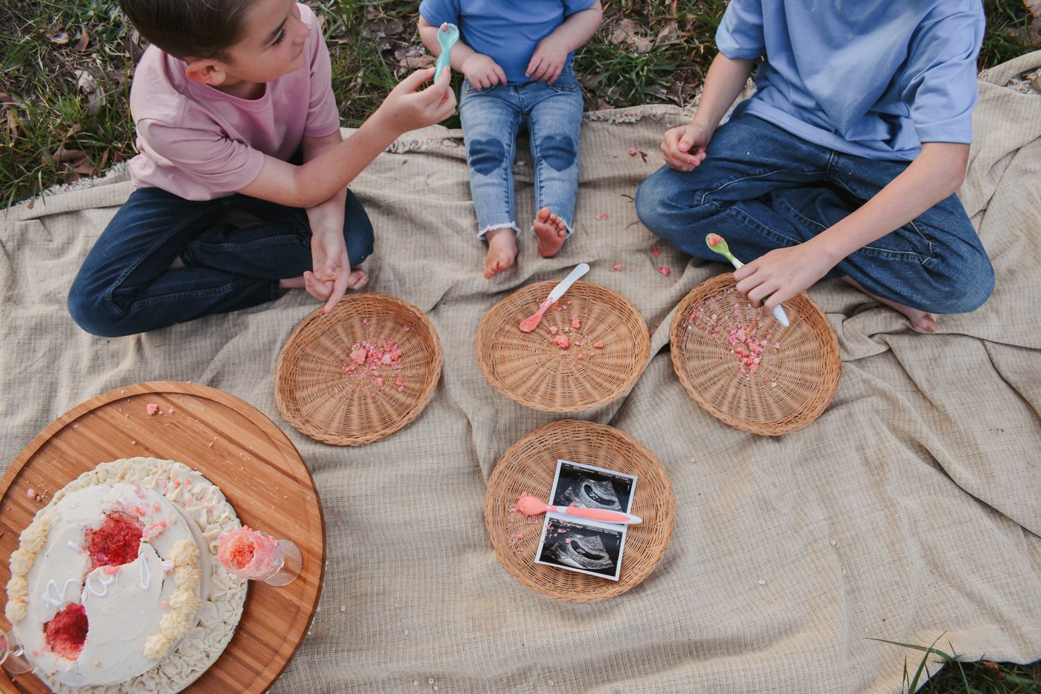 Children playing with decorative paper plates on picnic blanket.