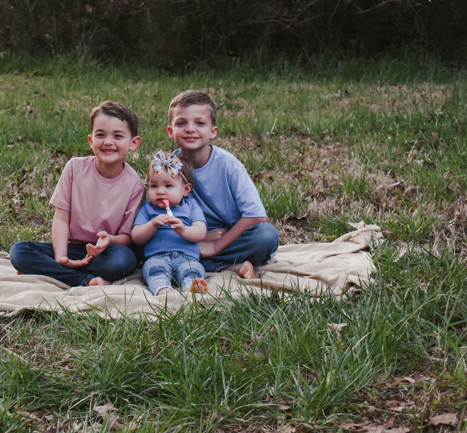 Kids relaxing together on blanket during outdoor celebration.