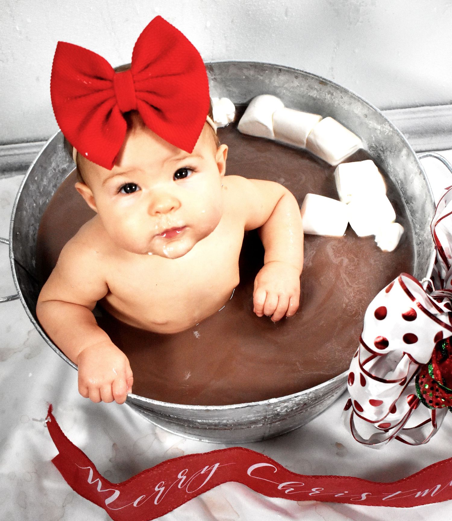 Christmas themed baby photo with metallic tub and red ribbon accents.
