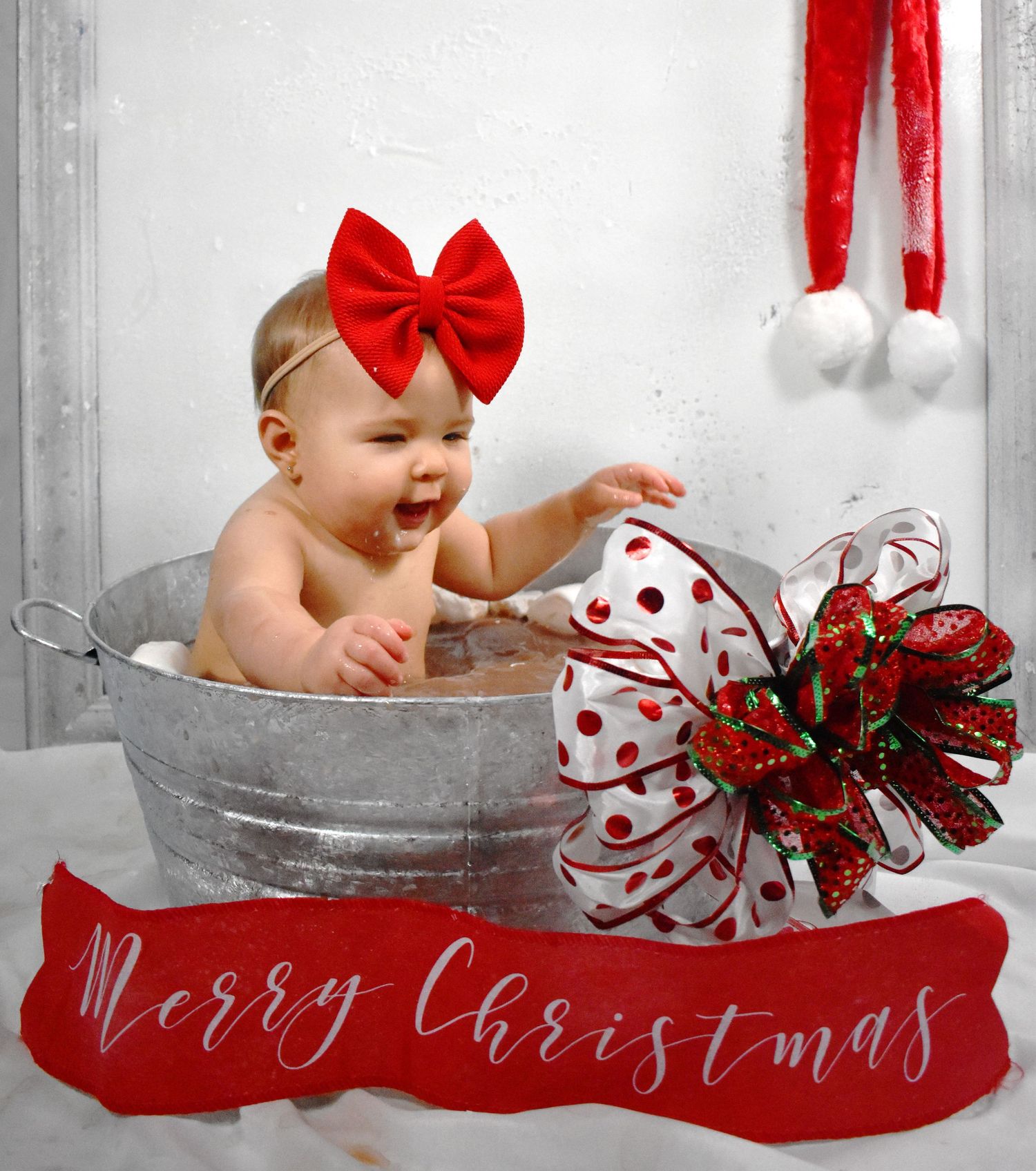 Festive Christmas photo featuring baby in galvanized tub with red and white decorations.