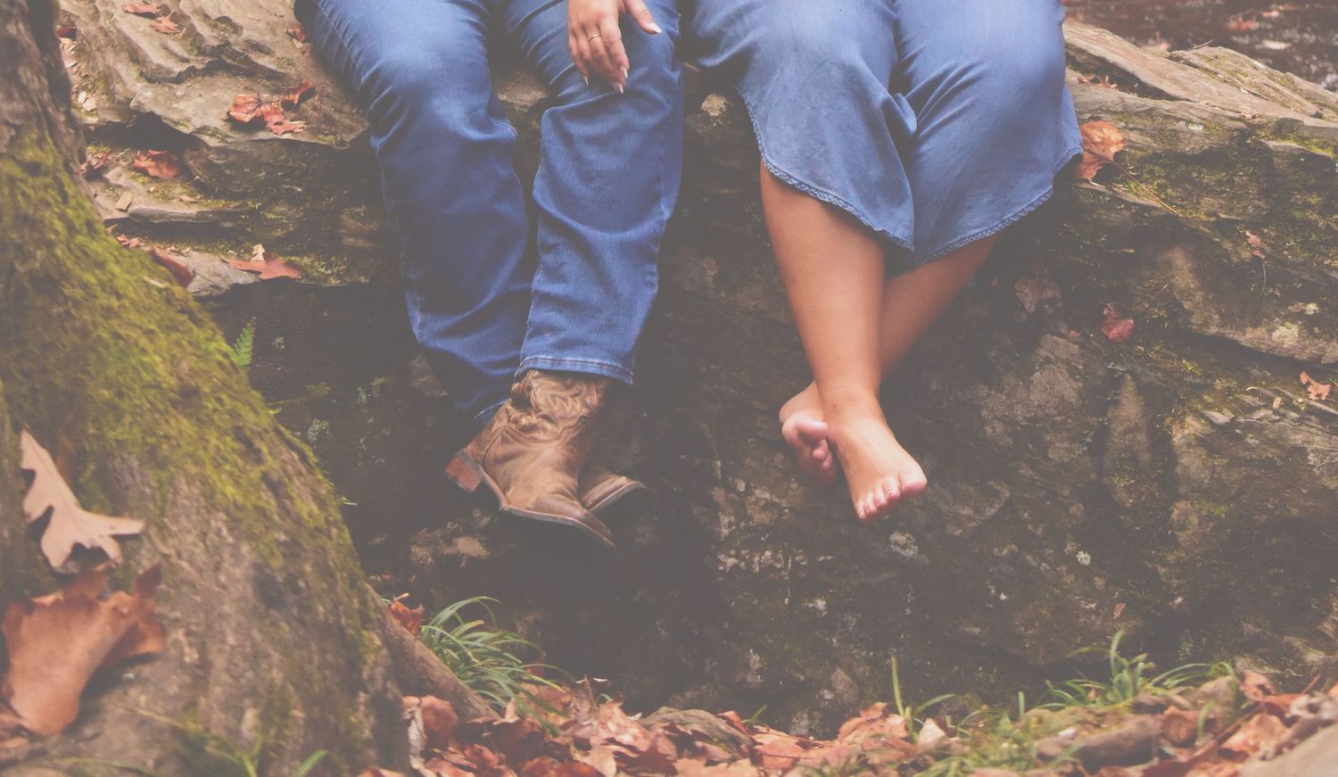Close-up of legs and feet resting on mossy ground covered in autumn leaves.