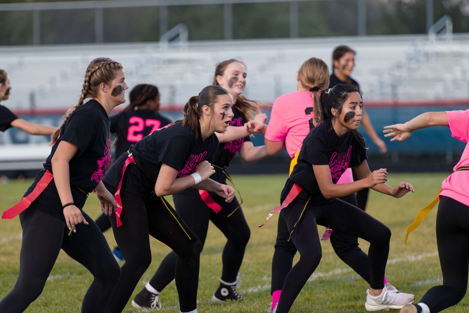 Athletes in black uniforms perform synchronized stretching exercises during outdoor training session.
