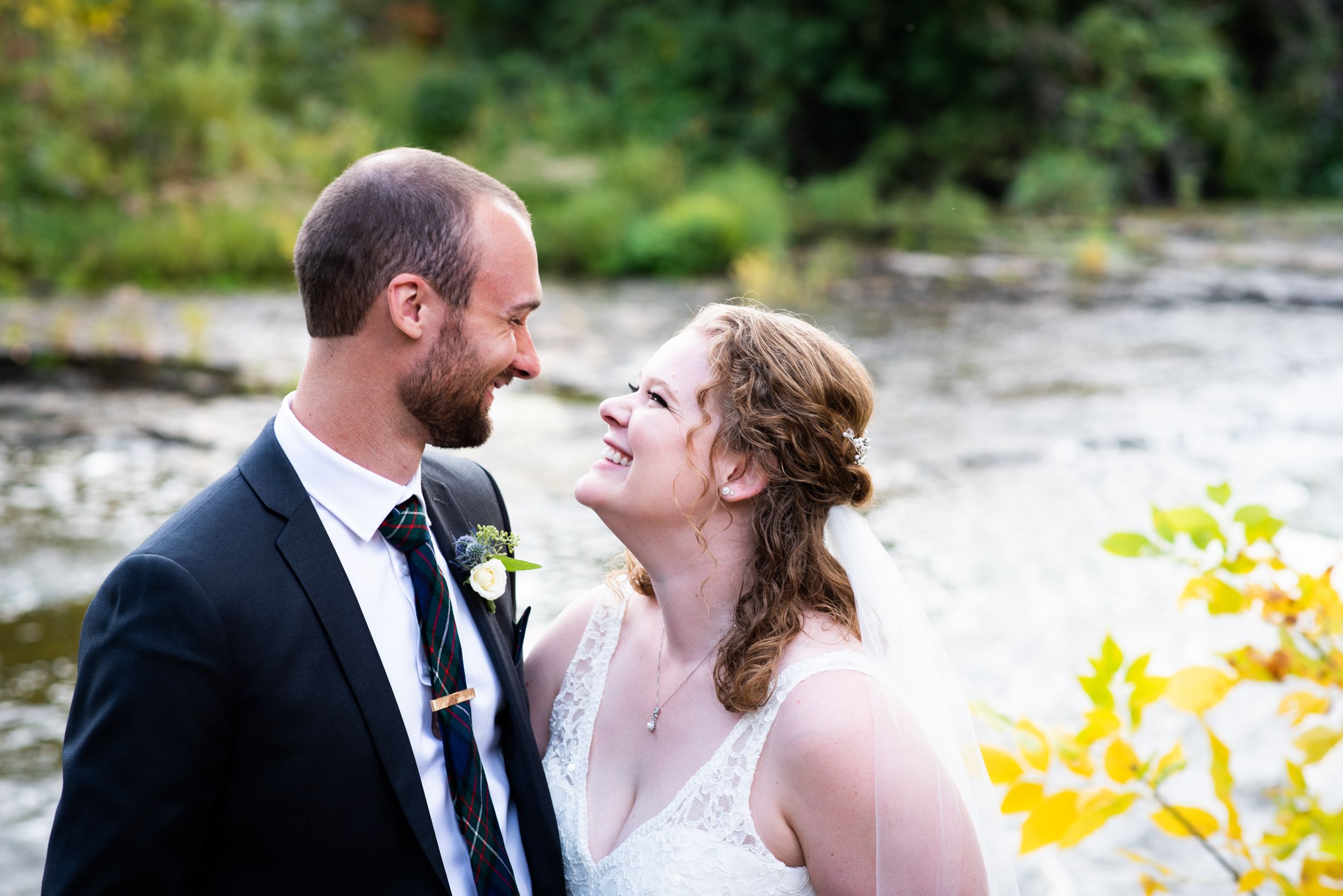 A romantic wedding portrait of a couple by a river during golden hour.