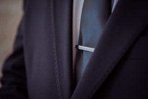 Close-up view of a dark blue suit jacket sleeve with a white shirt cuff visible underneath.