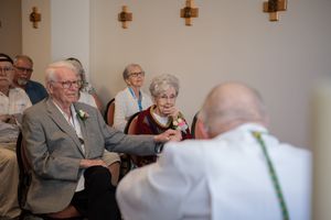 Attendees listen attentively during a conference session with wall-mounted lighting fixtures visible in the background.