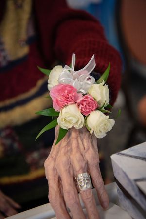Close-up of hands wearing delicate pink and white flower corsages with silver rings.