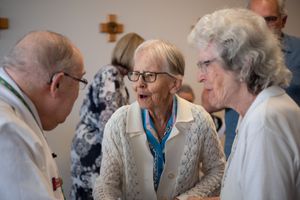 A group of elderly people sitting together and socializing in a bright indoor setting.