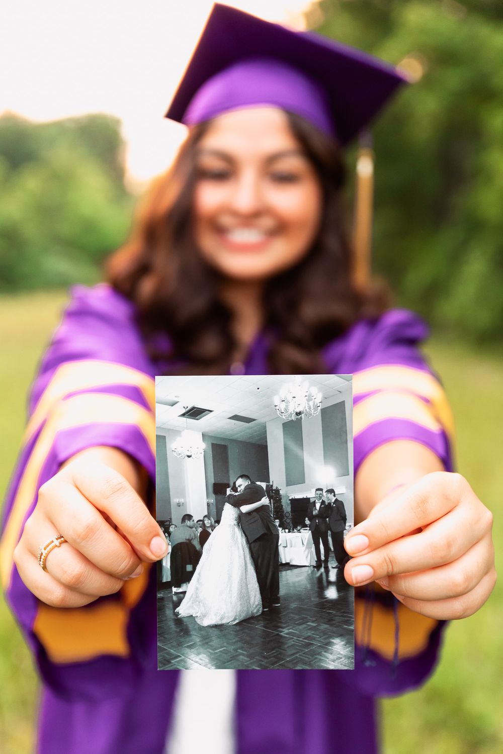 Hands holding black and white vintage photographs during graduation photoshoot.
