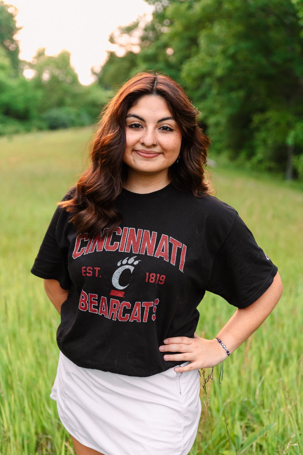 Student wearing Cincinnati Bearcats t-shirt poses outdoors for casual photos.