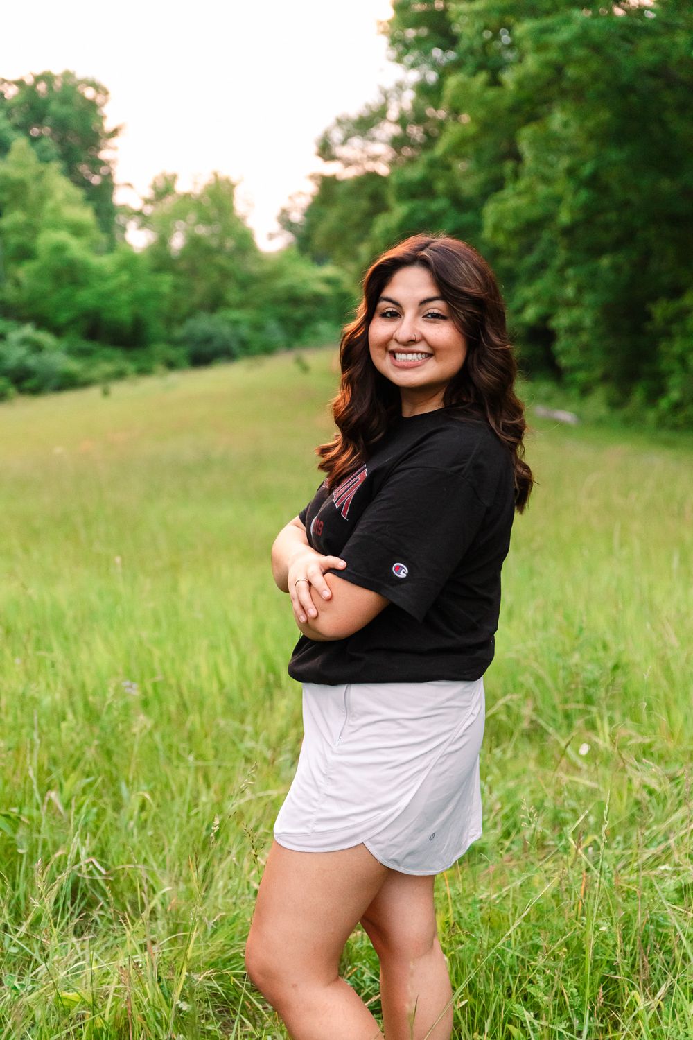 Casual outdoor portrait session in grassy field wearing Cincinnati university apparel.