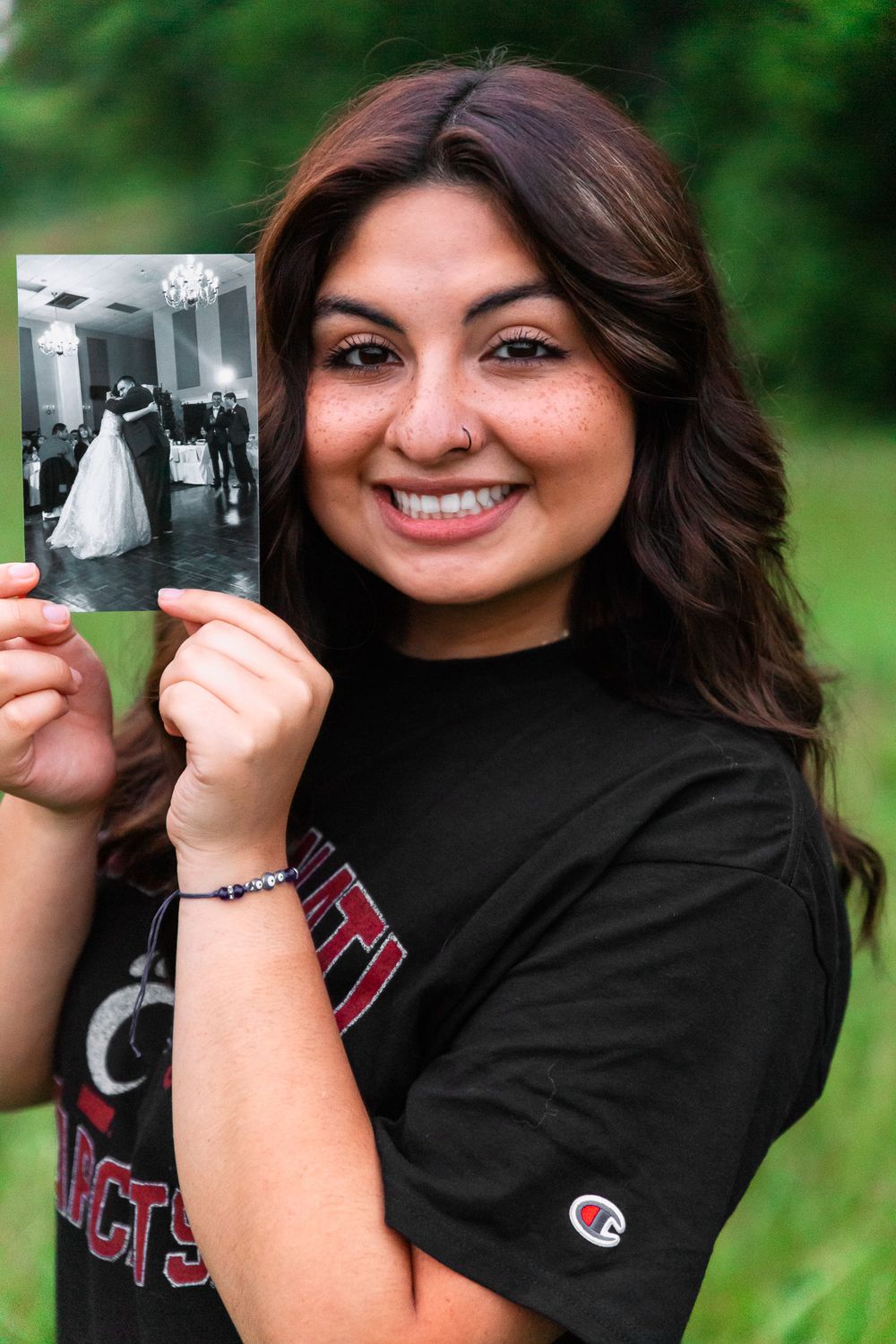 Person holding vintage photographs during outdoor portrait session wearing Champion shirt.