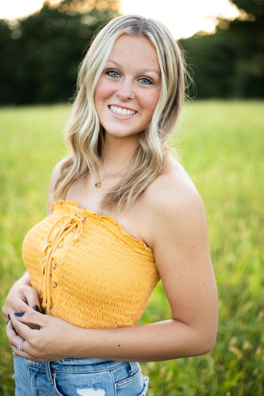 Portrait session in yellow crop top and jeans during golden hour lighting.