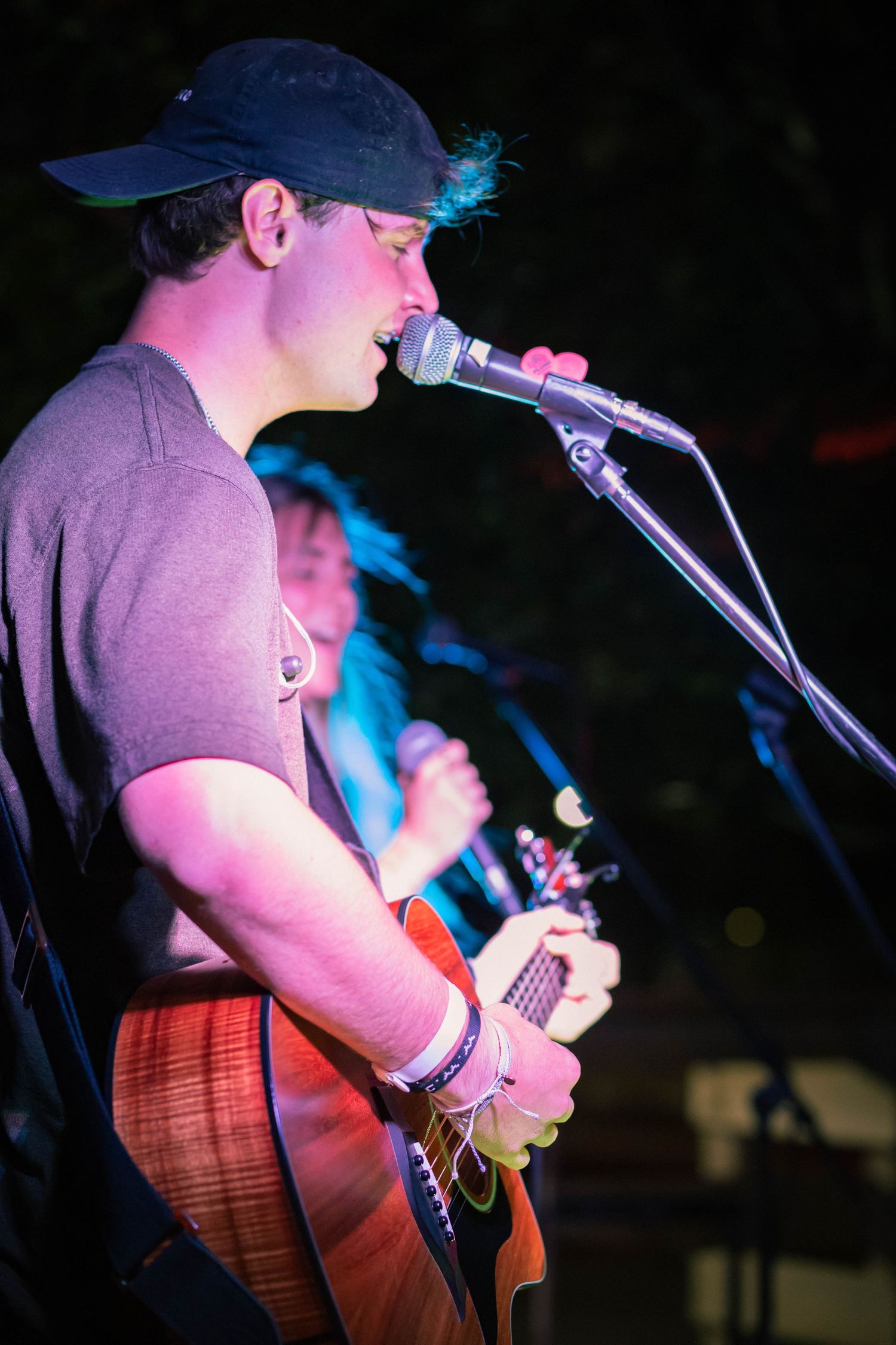 Musician performing on stage with guitar under blue spotlight.