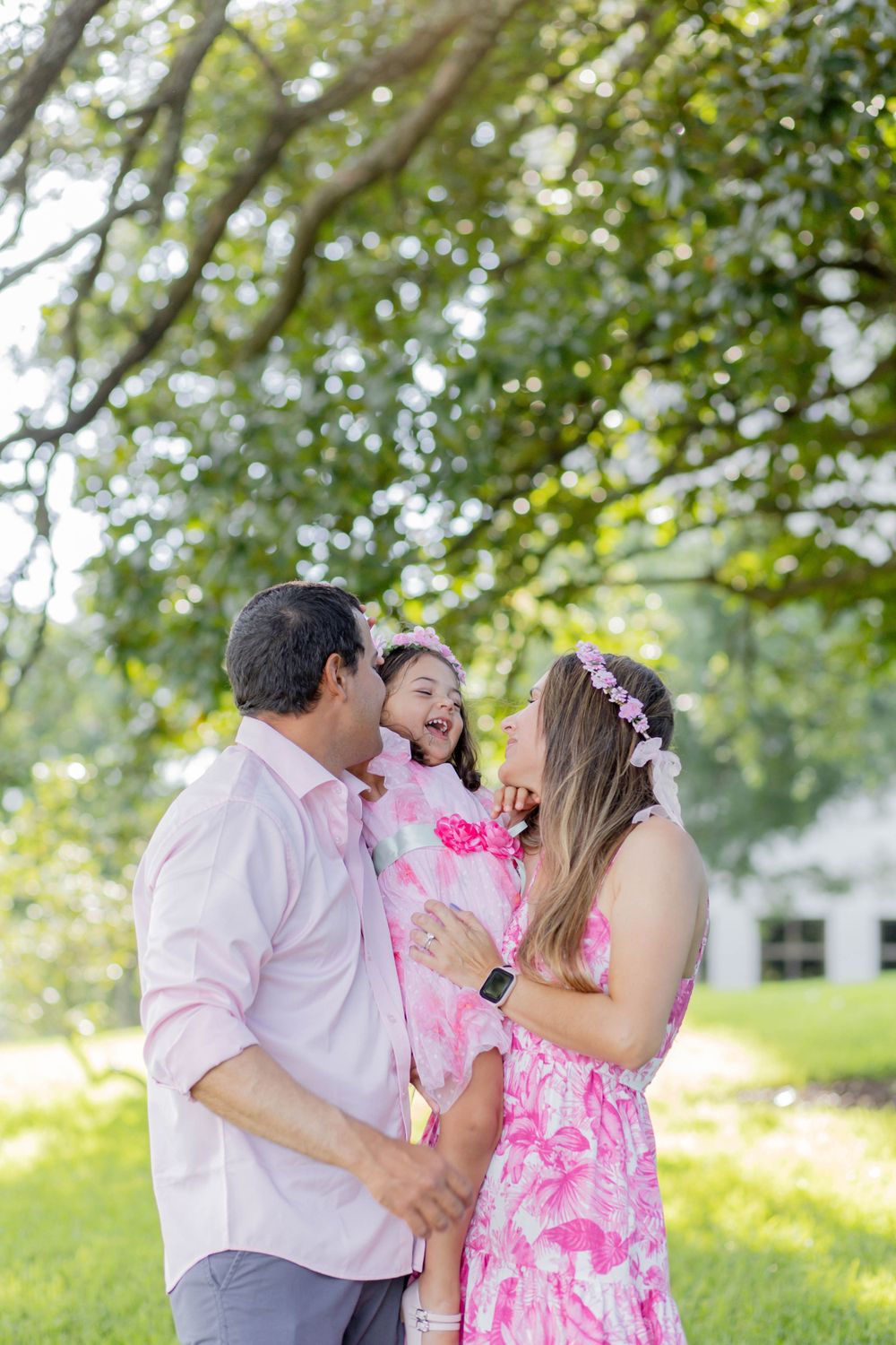 Family sharing laughter and joy together under trees in a sunlit park.