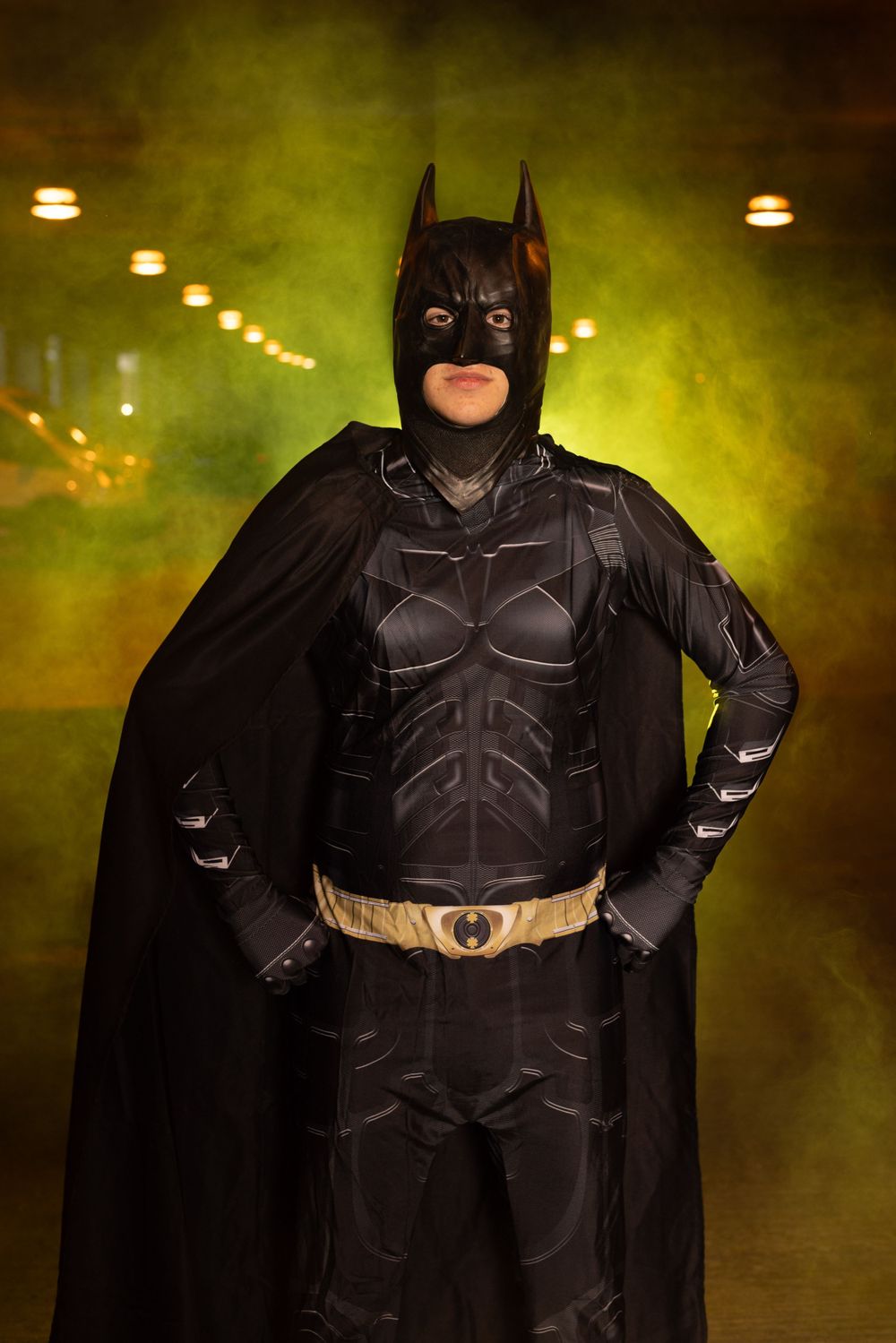 Batman cosplay photographed in moody green lighting with dramatic fog effects.