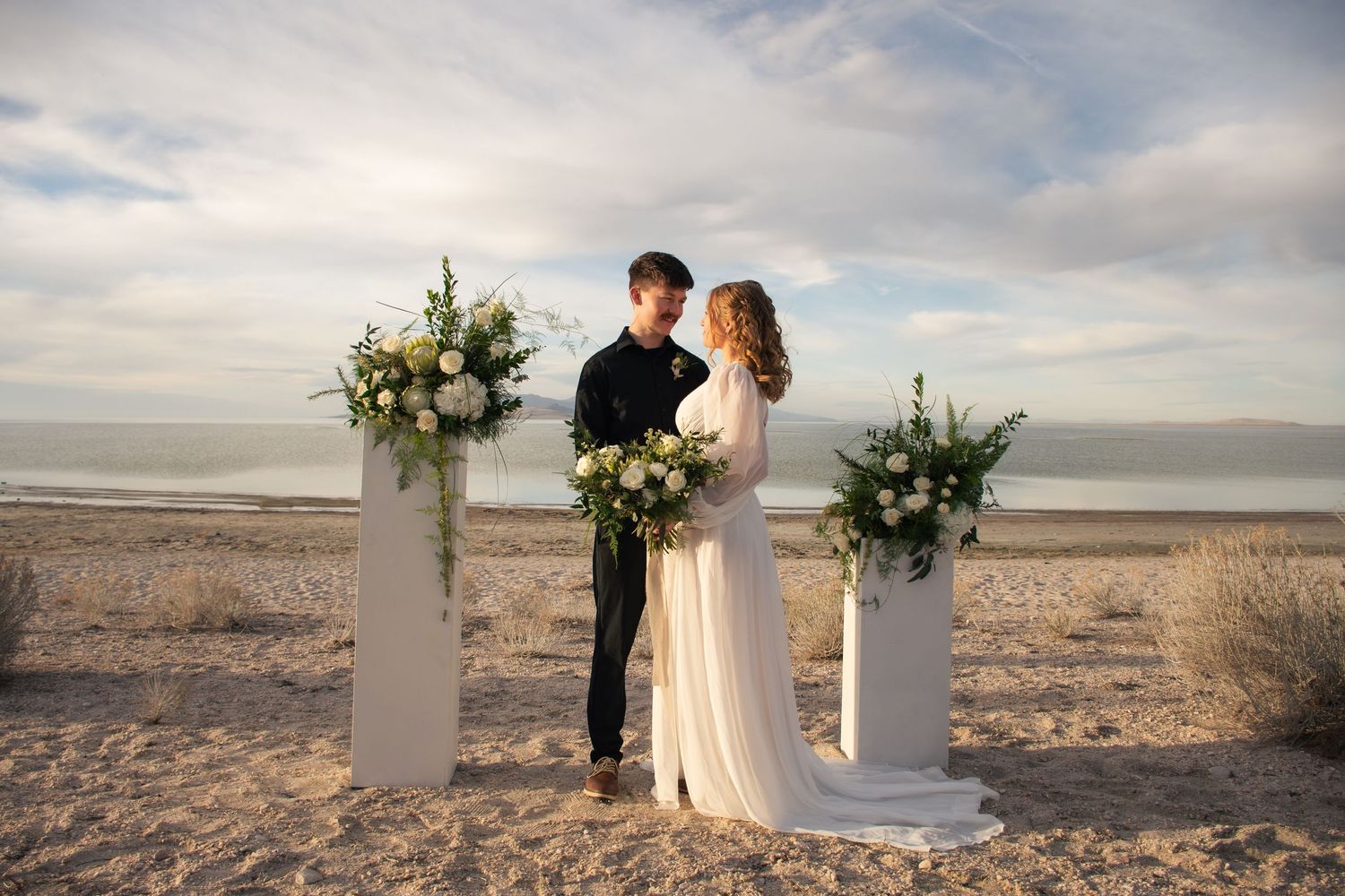 A bride and groom looks at each other in front of a cinematic landscape in Utah.
