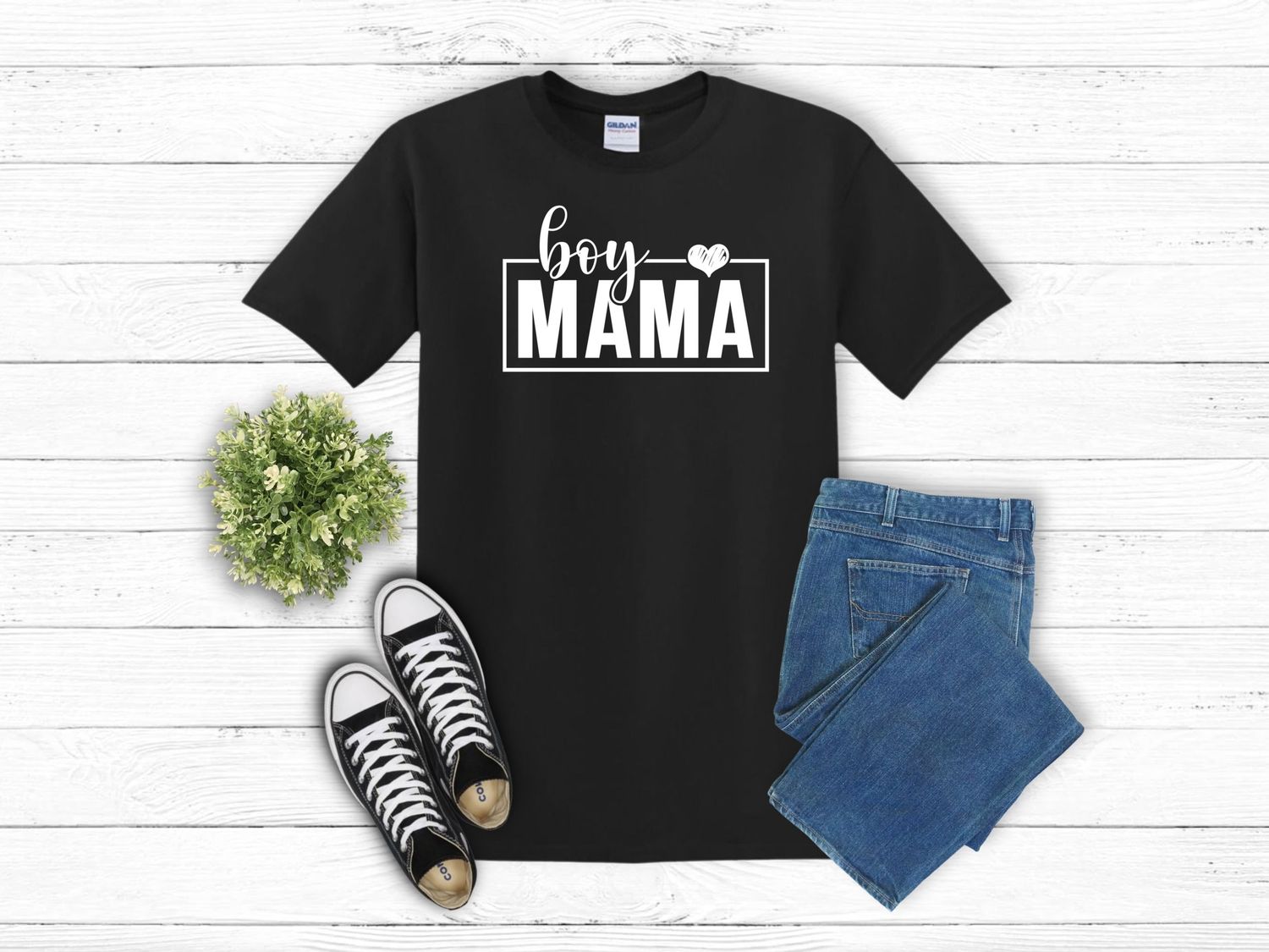 Flatlay featuring a black t-shirt with 'Mama' text, paired with blue jeans, sneakers and a small green plant.