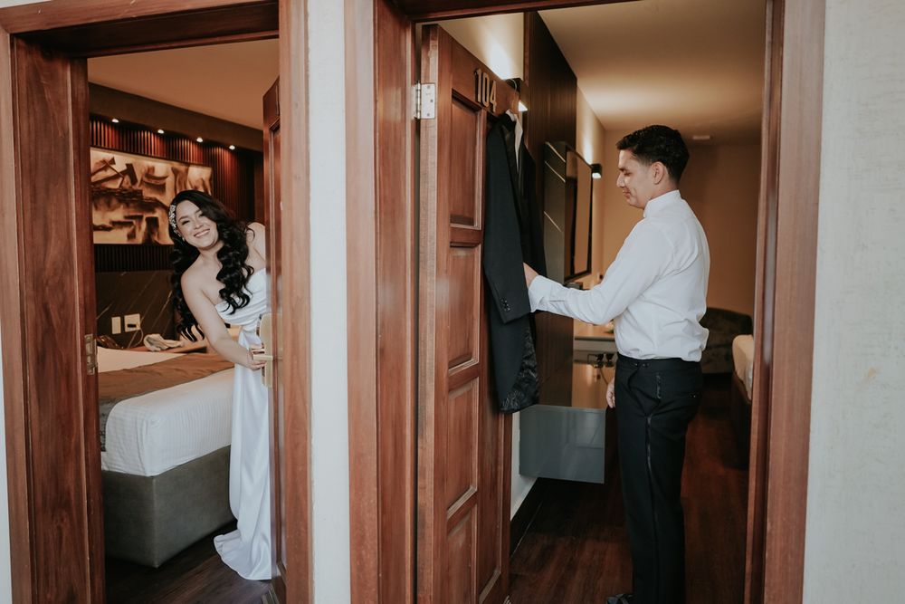 Two people in formal attire getting ready in separate hotel rooms with hanging clothes visible.