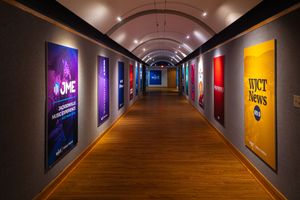 Long hallway with recessed lighting and colorful illuminated wall panels creates a modern and dramatic atmosphere.