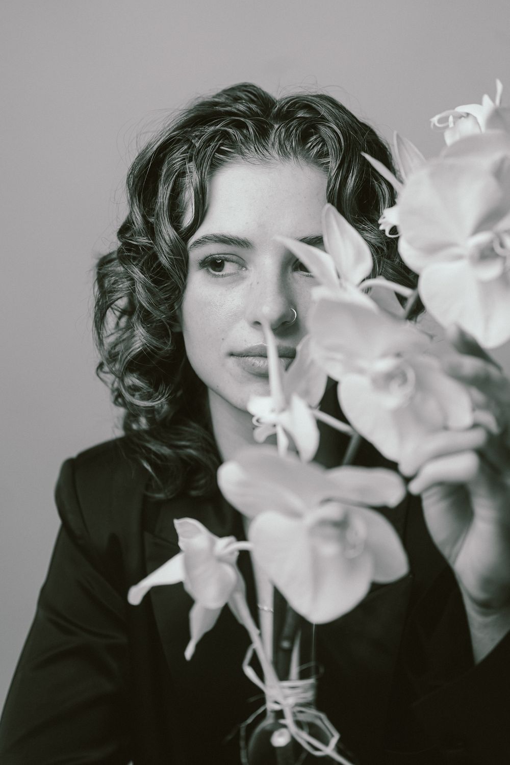 Artistic black and white portrait sequence showing white orchid flowers gradually obscuring a side profile view.