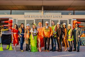A group of people wearing colorful dresses and outfits stand in a line outside a building.