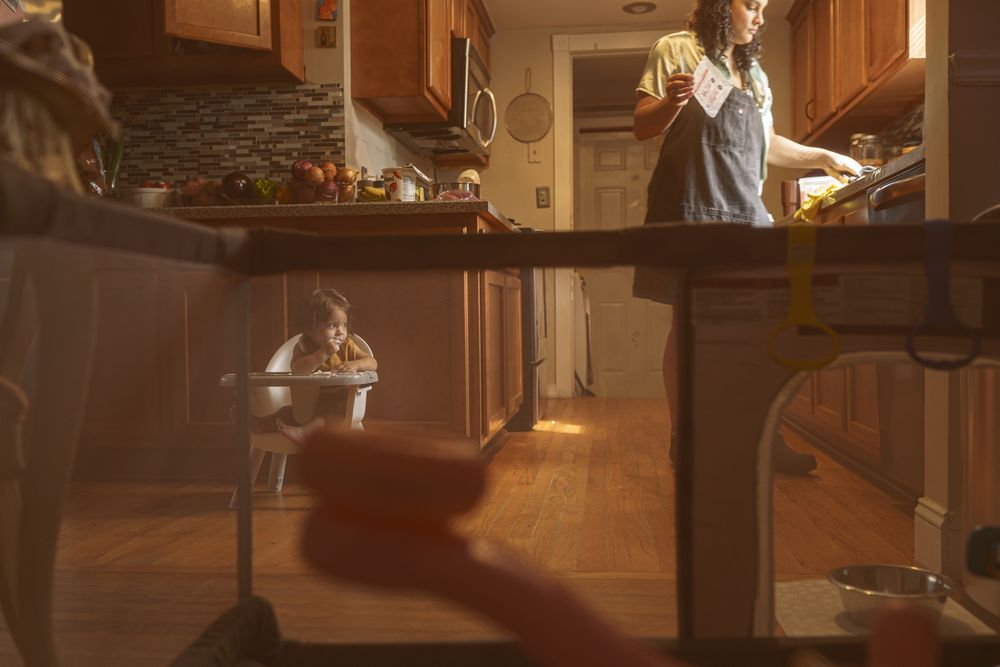 Warm sunlight streams through kitchen window as someone prepares food on wooden counter in rustic home setting.