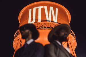 Orange baseball cap with DFLN text being shown from different angles against a dark background.