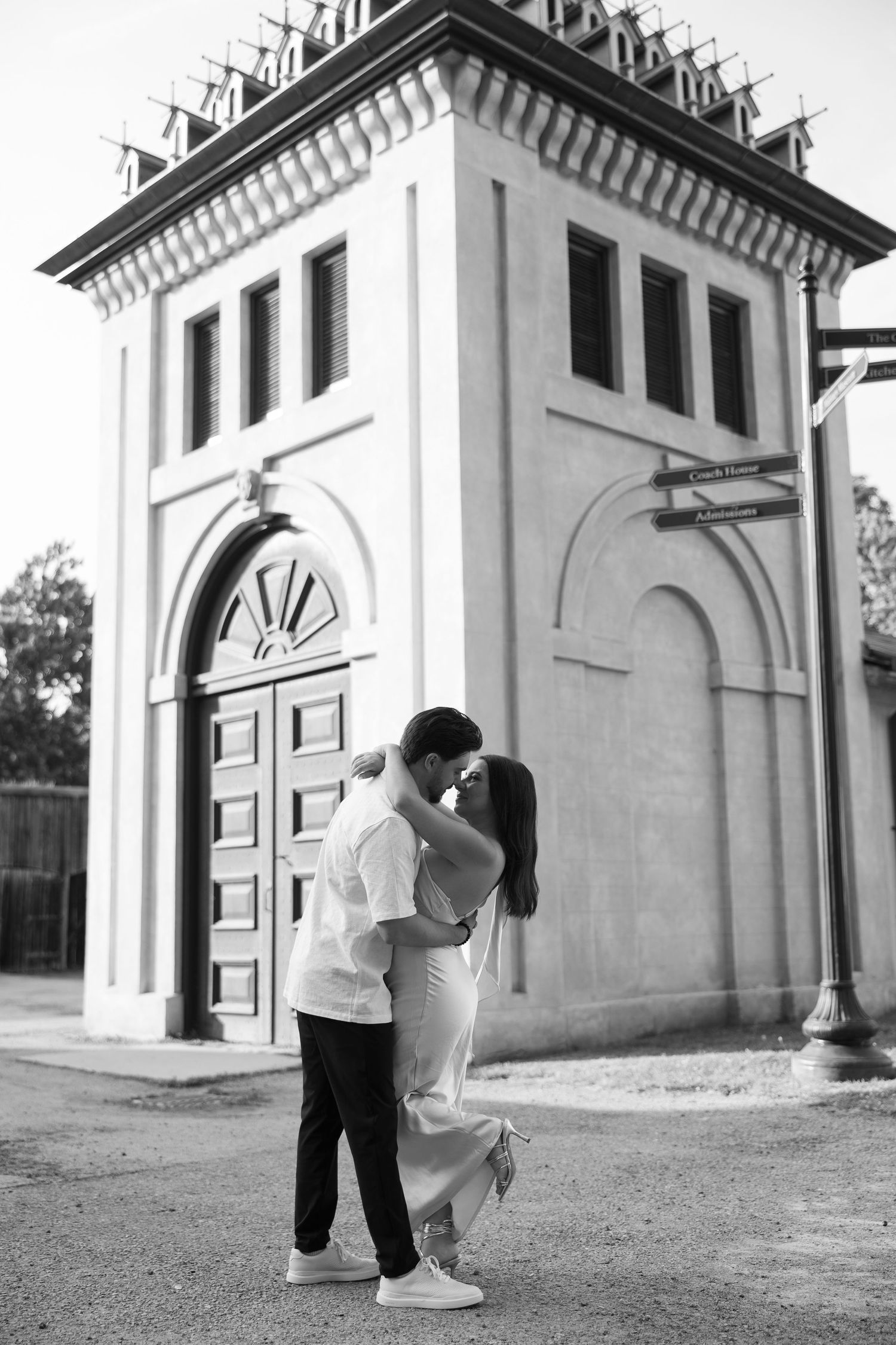 A romantic couple shares intimate moments in a series of black and white photos against a Mediterranean-style building.