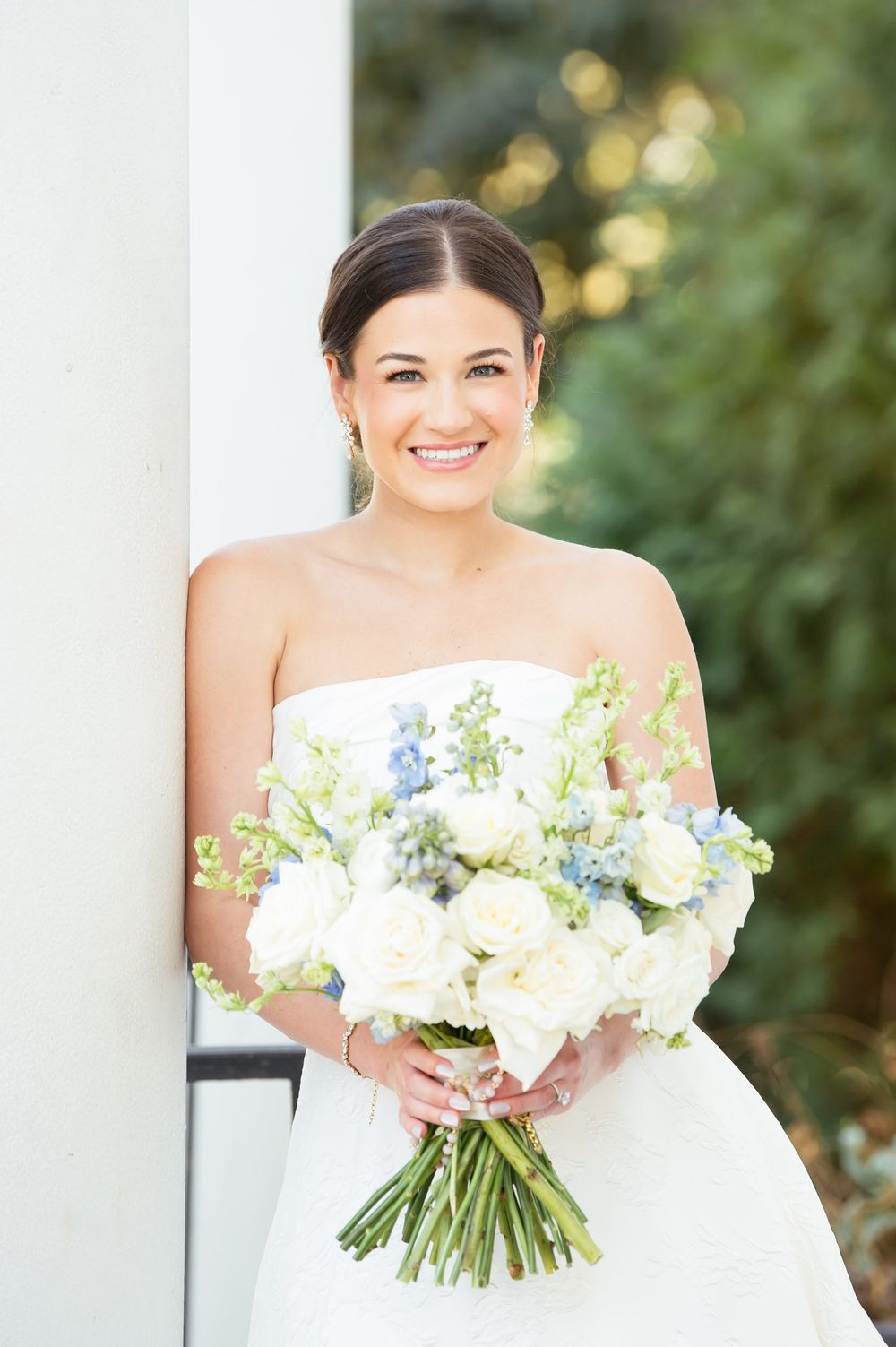 Elegant bridal portrait with lush white and blue bouquet against classic architecture.