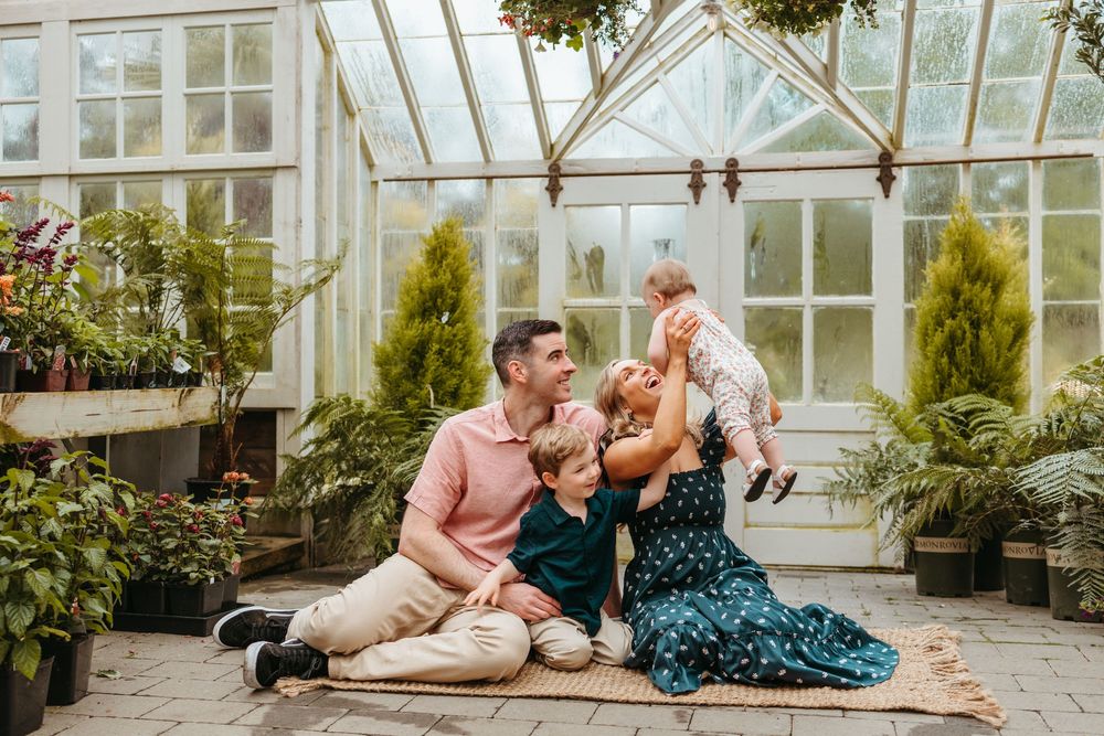 A couple shares intimate moments in a romantic greenhouse photoshoot with natural lighting and lush greenery.