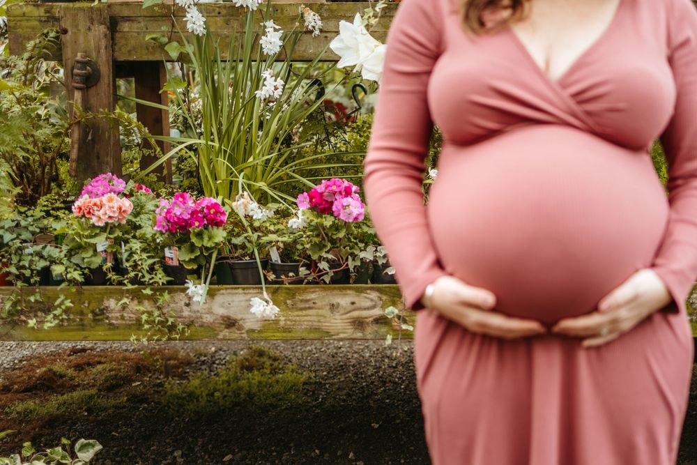 Collage of maternity photos showing a woman in a pink dress posing in a garden setting with blooming flowers.
