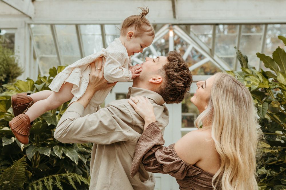 A joyful family moment captured in a greenhouse with plants surrounding them.