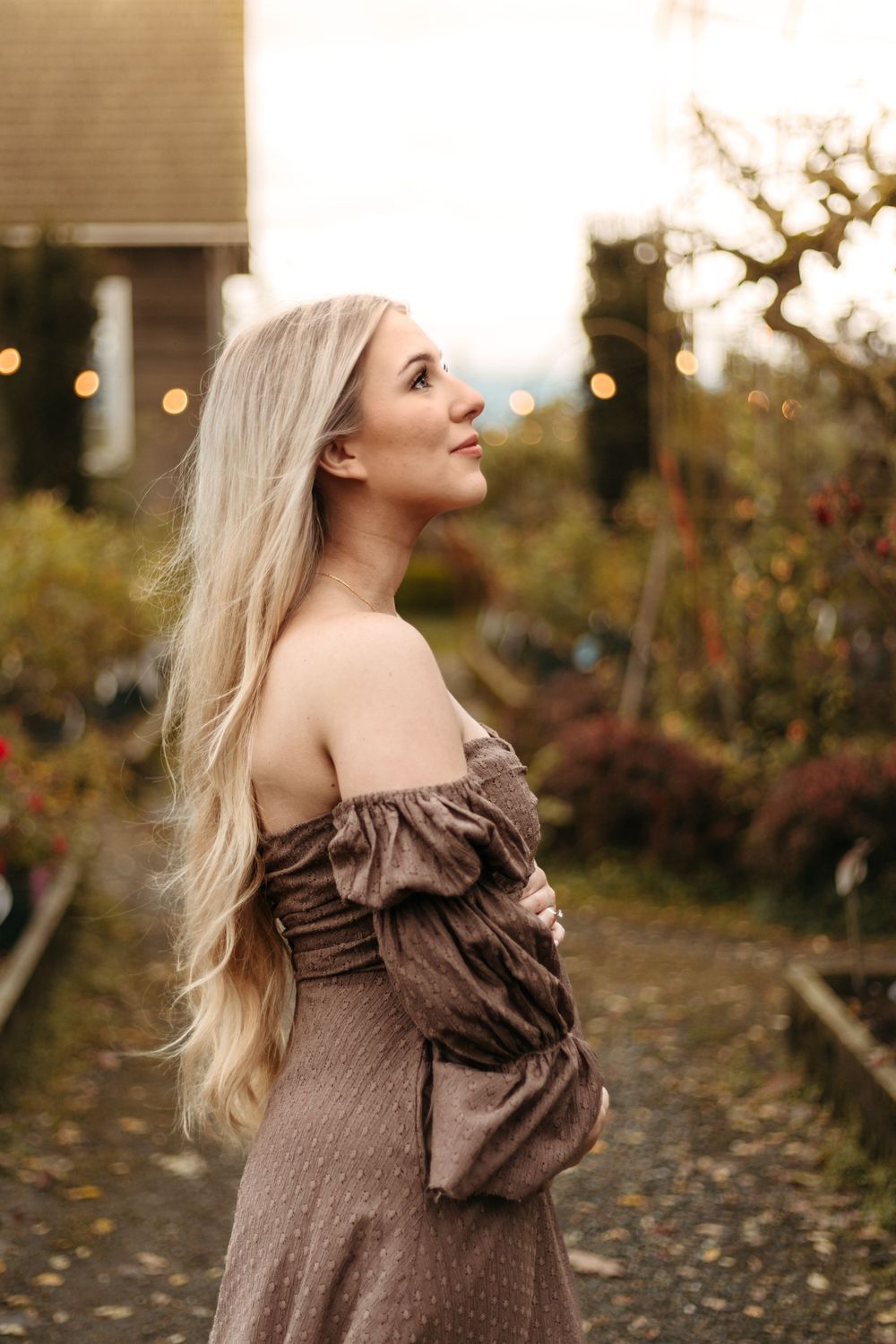 A side profile portrait in a brown dress against an autumn garden backdrop.