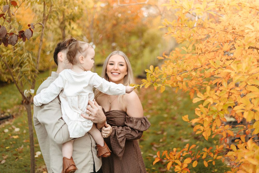 A family moment captured against vibrant fall foliage with golden sunlight.