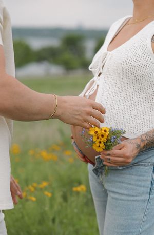 A person in a white crochet top holding a small bouquet of yellow wildflowers and lavender in a sunny meadow.