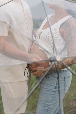 A couple in casual attire embraces romantically, with one person wearing white and the other in light denim.