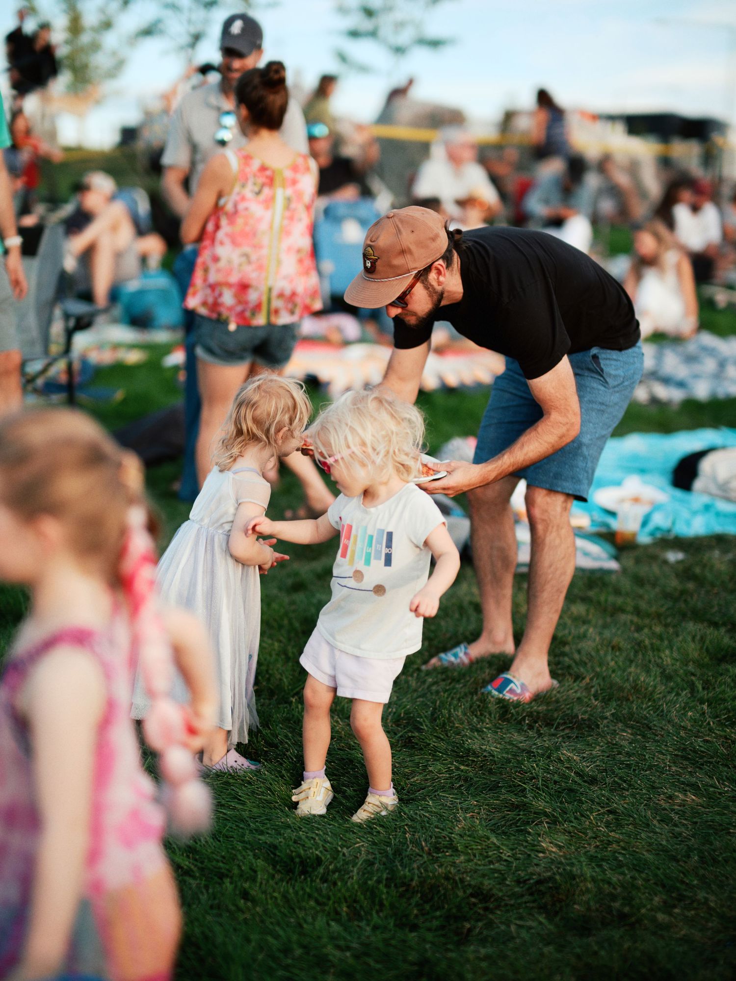 People enjoying an outdoor summer festival on a grassy lawn with children and adults gathered for entertainment.